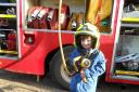 A reception pupil enjoys looking at the fire engine's equipment