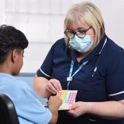 Lead immunisation nurse Yvonne Osborn helps a young boy choose a coloured sticker awarded to children who submit to a nasal influenza vaccine spray