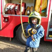 A reception pupil enjoys looking at the fire engine's equipment