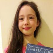 Eight-year old Eve Allen with her copy of Tom Fletcher's The Christmasaurus, which she loved so much she read it in two days