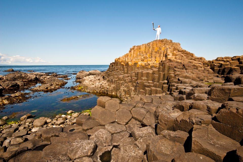 Relay: Torchbearer Peter Jack holding the Olympic Flame aloft on the Giant's Causeway in N. Ireland... 