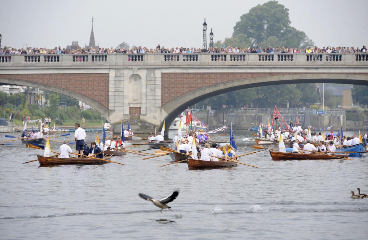 Rowing boats on the Thames near Kingston as the Olympic Flame is carried aboard the Royal row barge Gloriana...